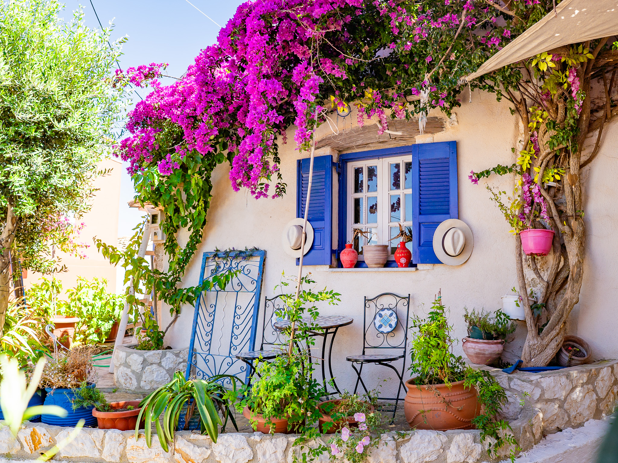 Wioska Afionas na Korfu z kwitnącą bugenwillą i turystami spacerującymi po uliczkach